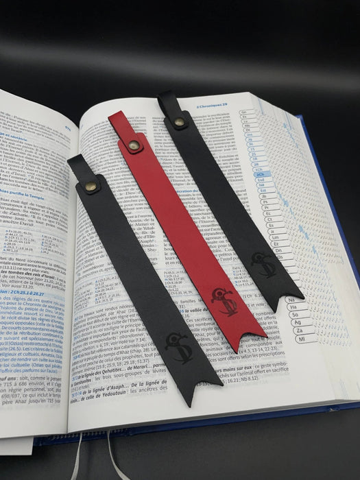 Trois marques page en cuir en noir ou rouge déposé sur une Bible 