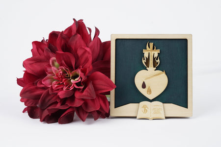 Cadre chrétien Sacré-Cœur de Paray-le-Monial en tilleul massif - Flammes dorées et couronne d'épines. Le fond est vert émeraude. Le cœur est traversé par un clou. Le cœur porte deux gouttes : une goutte de sueur gravée et une goutte de sang, peinte en rouge. Le feu qui entoure la croix positionnée sur le cœur est entouré de flammes dorées