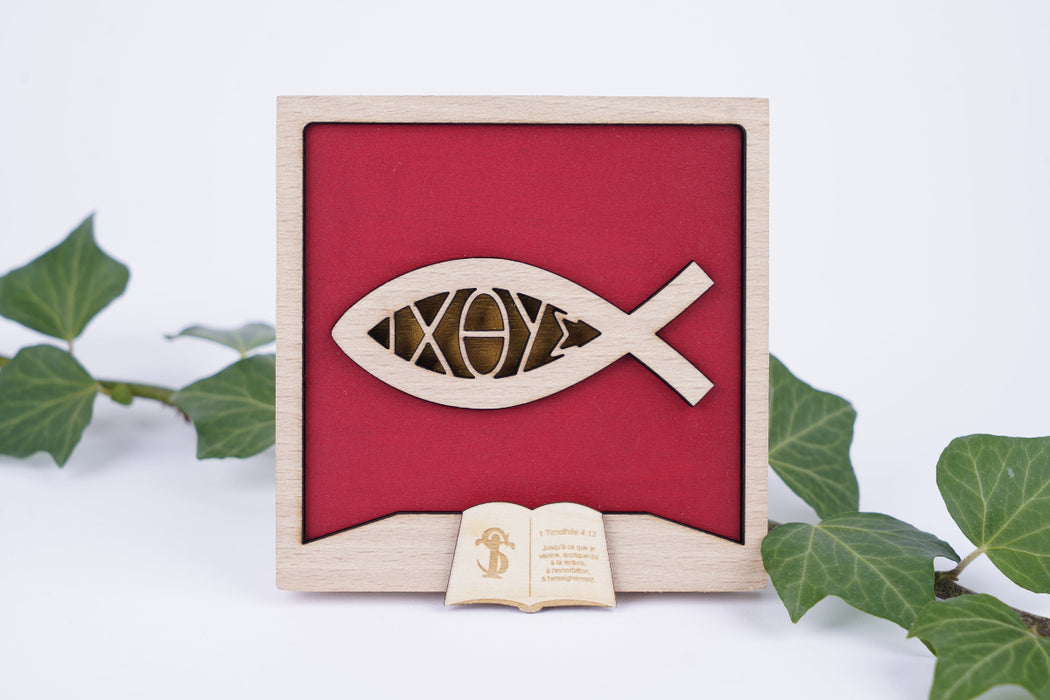 Cadre poisson avec l'inscription Ichthus. Le cadre est présenté débout entre des lierres. 