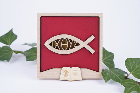 Cadre poisson avec l'inscription Ichthus. Le cadre est présenté débout entre des lierres. 