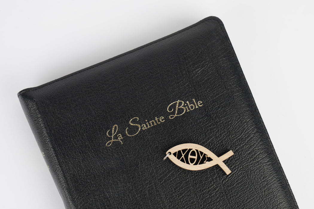 Pendentif poisson déposé sur une bible noire avec l'inscription "La Sainte Bible"