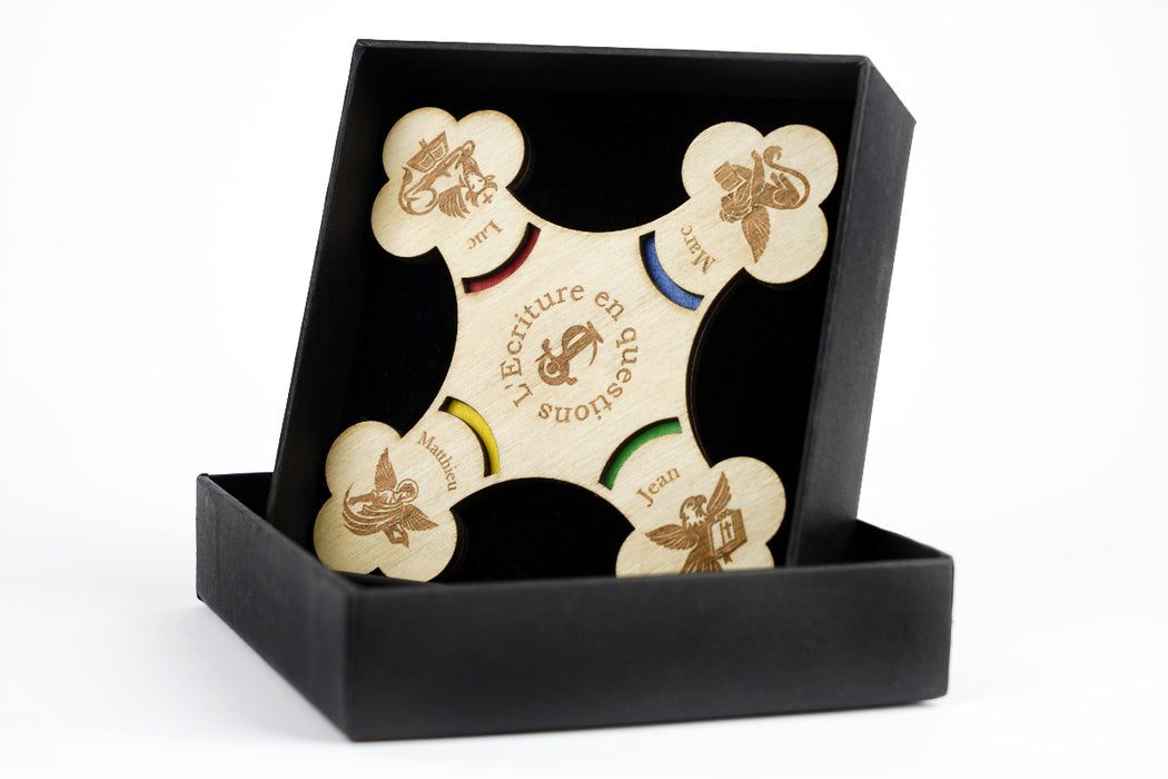 Quiz biblique positionné dans sa boite noire. Le quiz est représenté en forme de croix. 
A chaque extrémité de la croix, il y a le symbole des évangiles : le bœuf pour Luc, le lion pour Marc, l'aigle pour Jean et l'ange (ou l'homme) pour Matthieu.