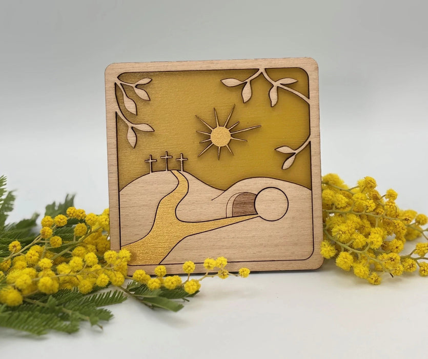 Cadre décoration religieuse chrétienne pour Pâques représentant les trois croix et le tombeau du Christ. La décoration est mise en valeur avec des branches de mimosas